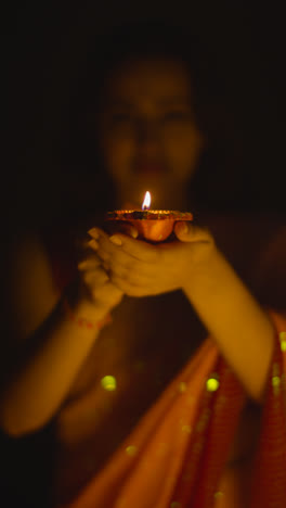 Video-Vertical-Cerca-De-Una-Mujer-Celebrando-El-Festival-De-Diwali-Sosteniendo-Una-Lámpara-De-Aceite-Diya-Encendida